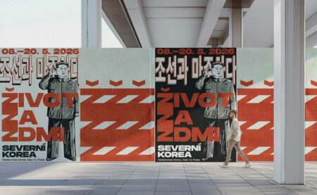 Poster wall advertising a North Korea exhibit: a stylized man saluting, bold red geometric patterns, and text including 'SEVERNÍ KOREA' with dates 08–20.5.2026.
