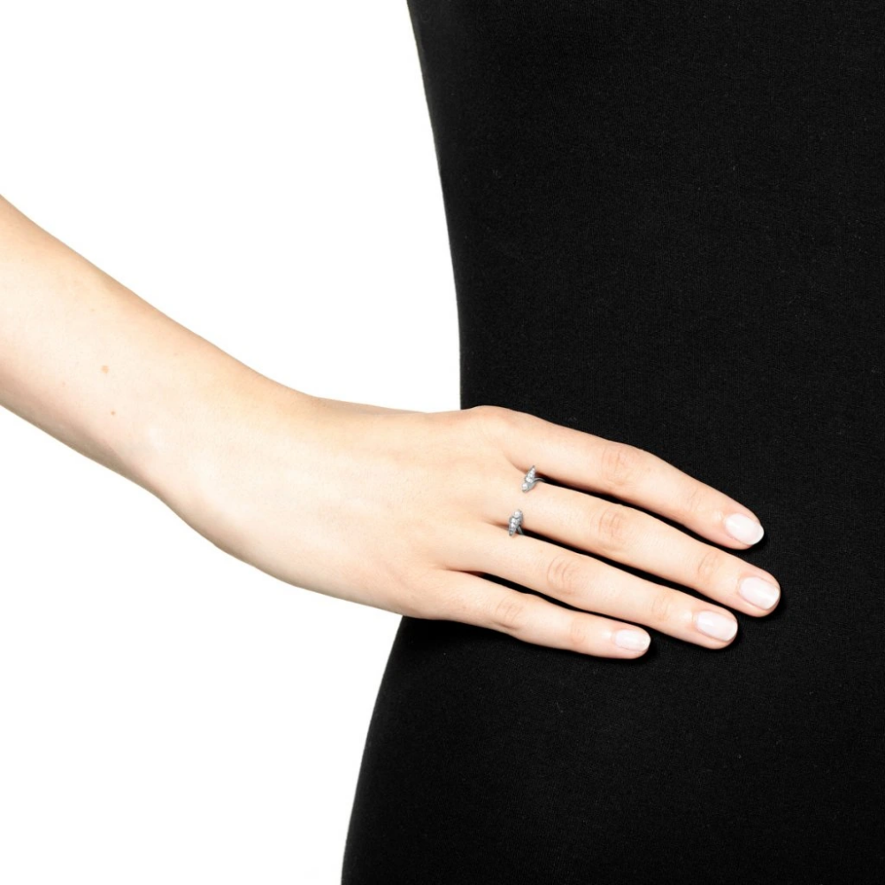 A hand resting on a black fabric background, wearing two small diamond rings on the ring finger.
