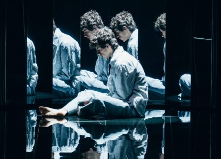 Promo image for Eurovision 2026: a man sits on a mirrored black stage; Czechia First Look logo at bottom.