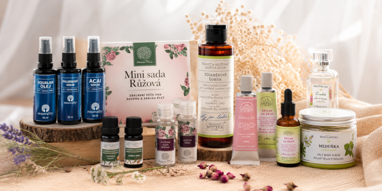 Assorted natural skincare products displayed on a wooden platform with dried flowers and a pink floral box behind them.