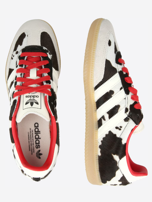 Adidas sneakers with a white and black cow-print pattern, red laces, and tan gum soles (top and side views).