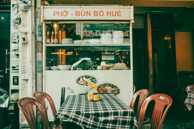 Vietnamese street food stall with bowls, herbs, and a checkered table for dining outside the counter area