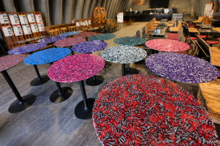 Colorful round mosaic tables with black pedestal bases arranged in a cafe or event space showroom.