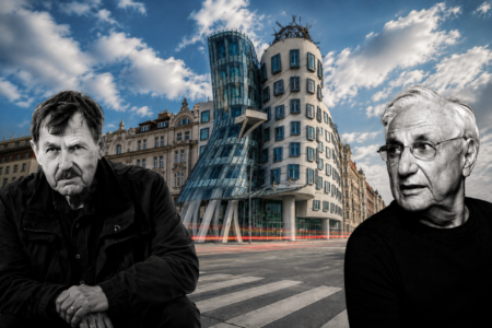 Two older men in dark clothing sit at a crosswalk in front of Prague's iconic Dancing House against a blue sky with clouds.