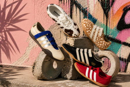 Six Adidas sneakers arranged on concrete blocks in front of a colorful graffiti wall.