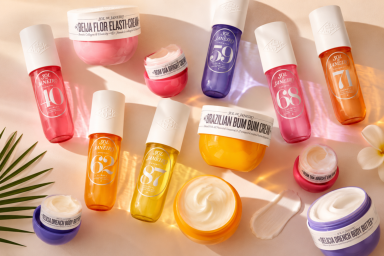 Assorted Sol de Janeiro hair/body care products in bright pink, yellow, orange, and purple bottles on a pastel backdrop.