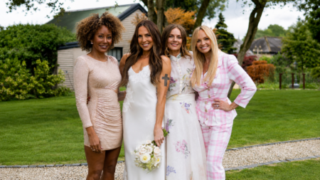 Four women pose together in a garden, one in a white lace wedding dress holding a bouquet, flanked by friends in a beige sequin dress, floral dress, and pink plaid suit.